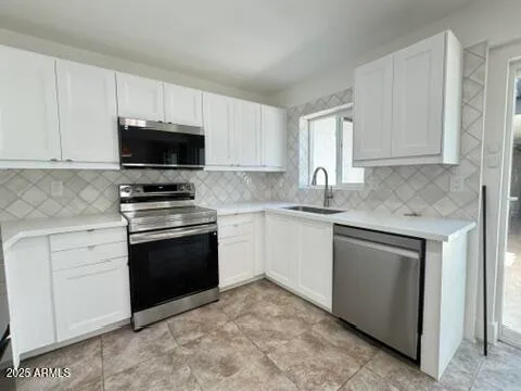 a kitchen with granite countertop white cabinets and stainless steel appliances