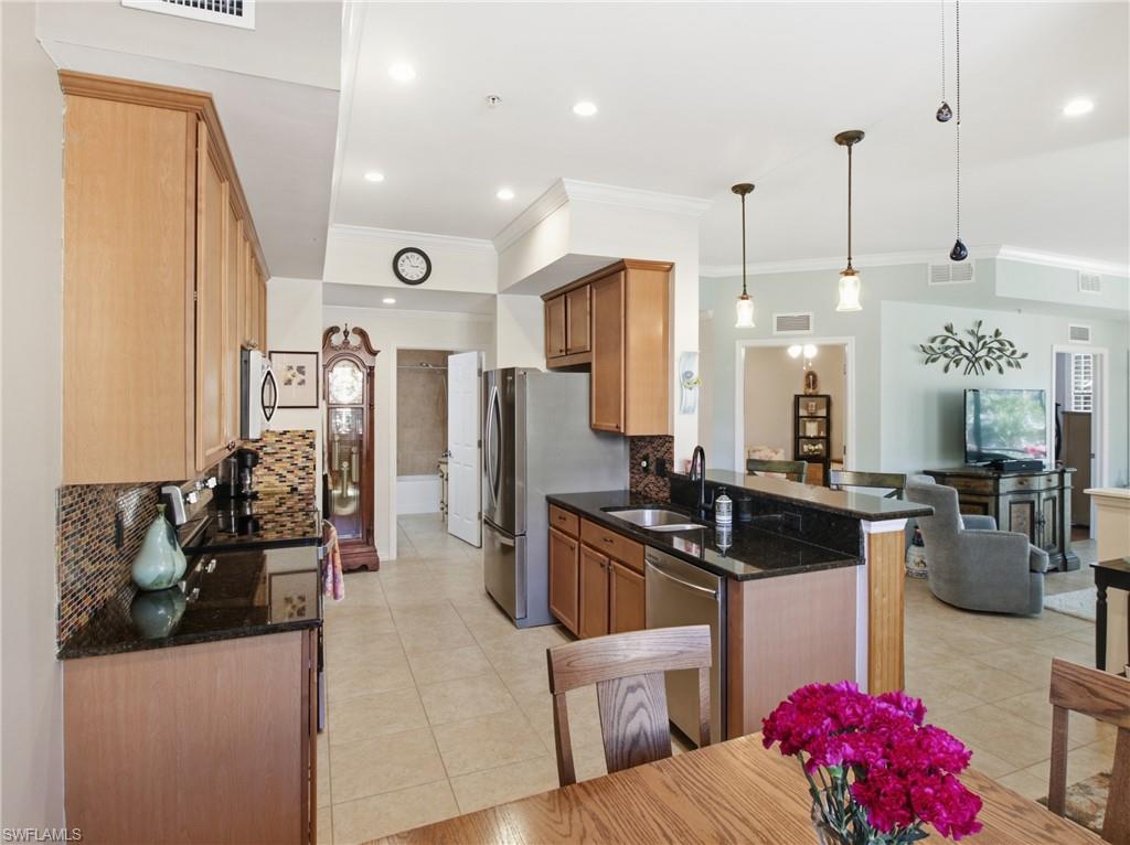 20161 Bravada Street, Unit 2 Estero, FL 33928 - Photo 11 of 34 Kitchen with tasteful backsplash, stainless steel appliances, hanging light fixtures, dark stone counters, and ornamental molding