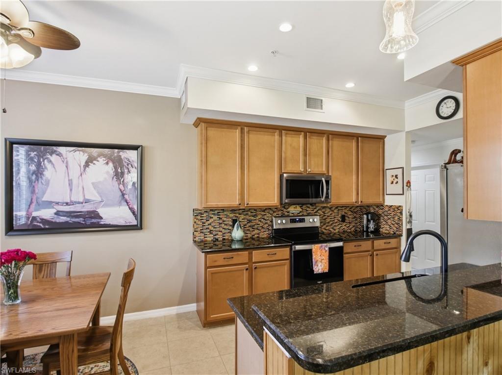 20161 Bravada Street, Unit 2 Estero, FL 33928 - Photo 12 of 34 Kitchen with stainless steel appliances, dark stone counters, decorative backsplash, ornamental molding, and a peninsula
