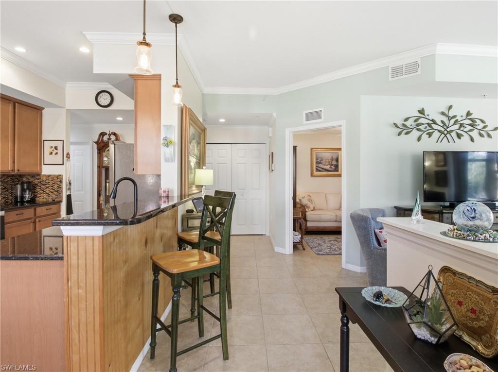 20161 Bravada Street, Unit 2 Estero, FL 33928 - Photo 8 of 34 Kitchen with a breakfast bar, dark stone counters, wood finish cabinetry, tasteful backsplash, and decorative light fixtures