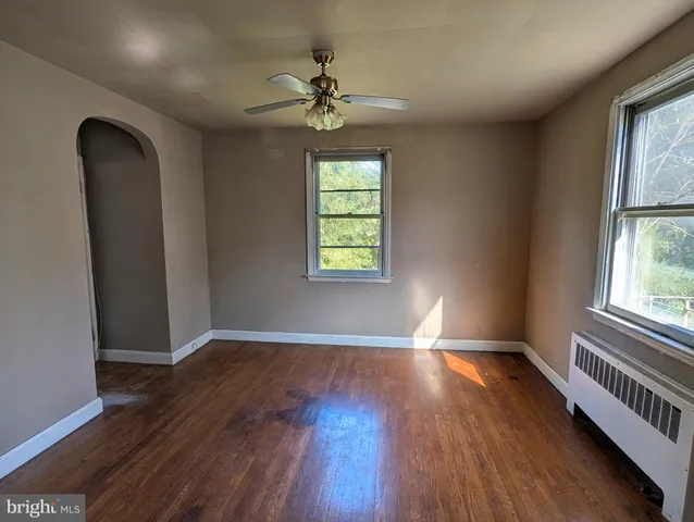 an empty room with wooden floor chandelier and windows