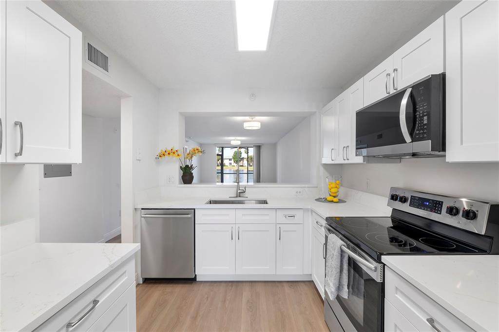 7763 Southampton Terrace, Unit 102 Tamarac, FL 33321 - Photo 11 of 73 a kitchen with a sink a stove and cabinets