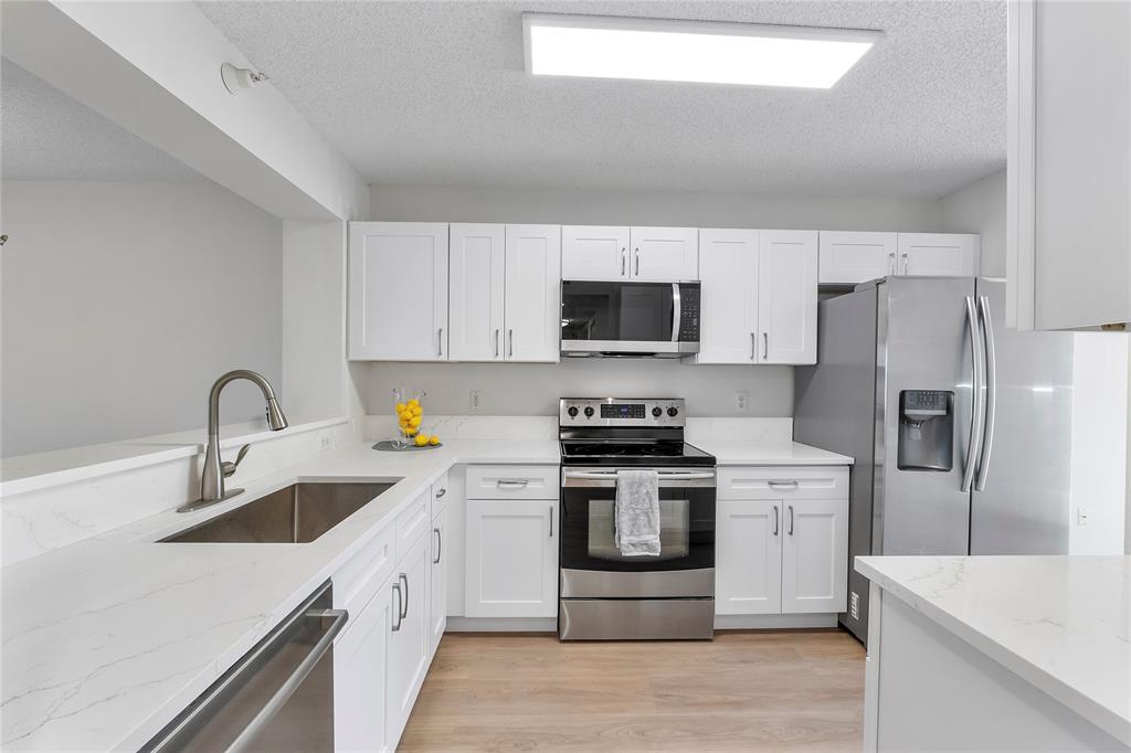 7763 Southampton Terrace, Unit 102 Tamarac, FL 33321 - Photo 12 of 73 a kitchen with stainless steel appliances granite countertop a sink a stove a refrigerator cabinets and a sink