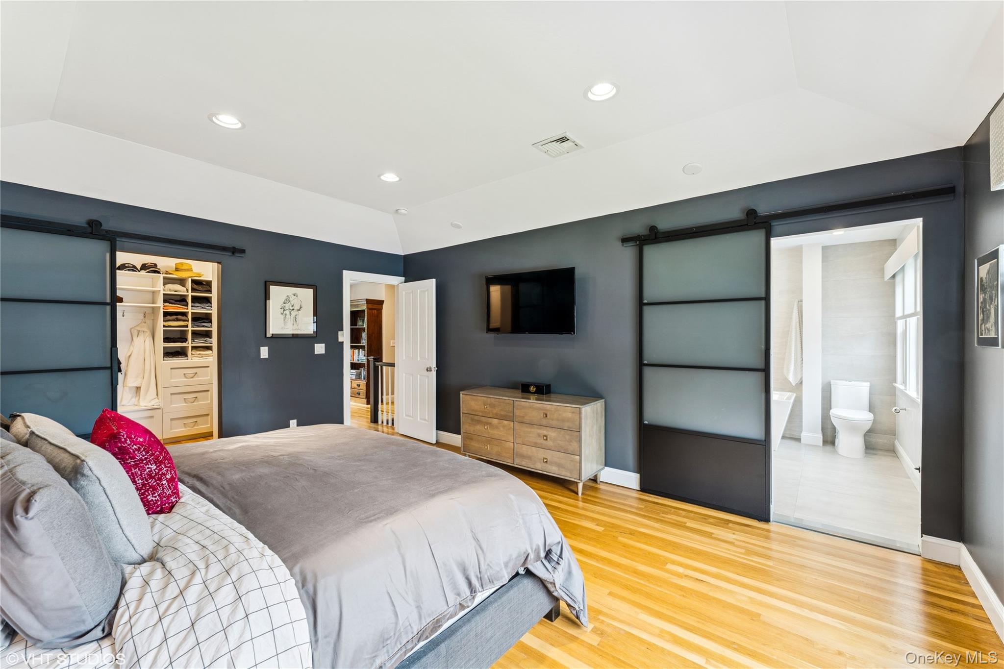 15 Flamingo Road East Hills, NY 11576 - Photo 21 of 41 Bedroom featuring a barn door, connected bathroom, wood floors, lofted ceiling, and a spacious closet