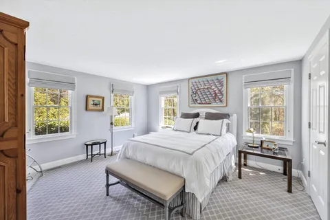 a bedroom with a large bed wooden floor and lamp next to a window