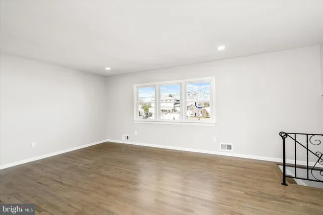 an empty room with wooden floor and window