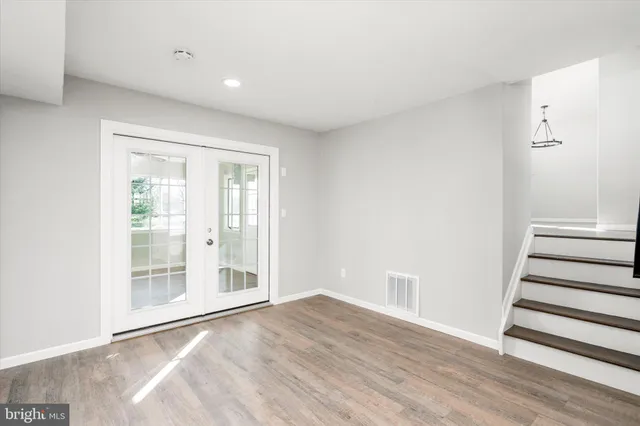 a view of an empty room with wooden floor and windows