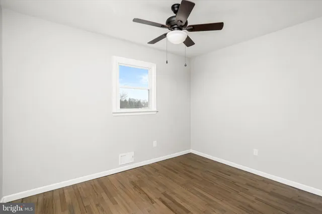 an empty room with wooden floor and a ceiling fan