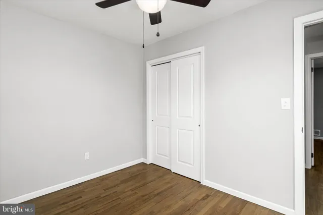 an empty room with wooden floor cabinet and ceiling fan