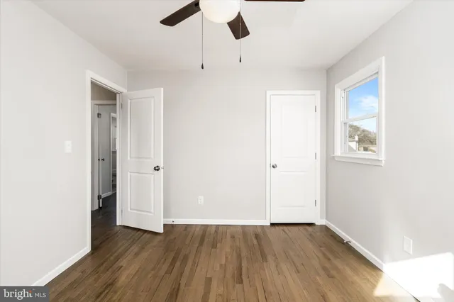 an empty room with wooden floor cabinet and windows