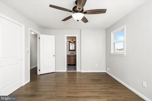 an empty room with wooden floor chandelier fan and windows