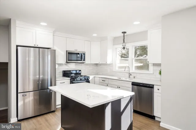 a kitchen with a sink a refrigerator a stove and white cabinets