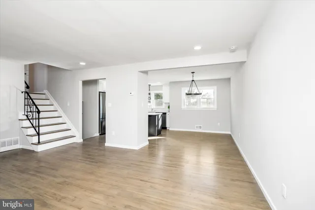 a view of an empty room with wooden floor and kitchen