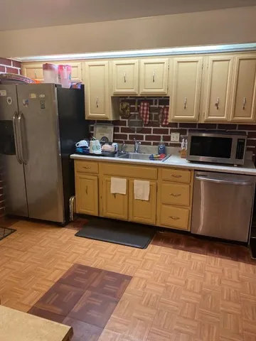 a kitchen with stainless steel appliances a refrigerator a sink and white cabinets