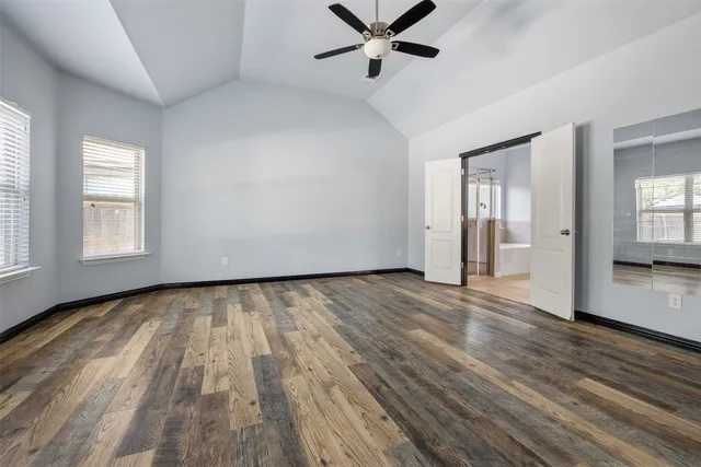 a view of an empty room with wooden floor and windows