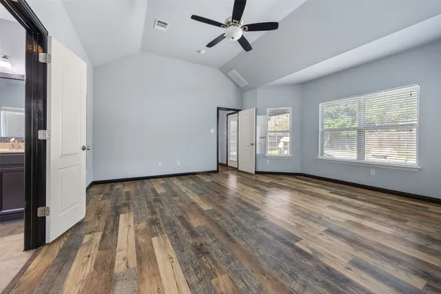 an empty room with wooden floor and windows
