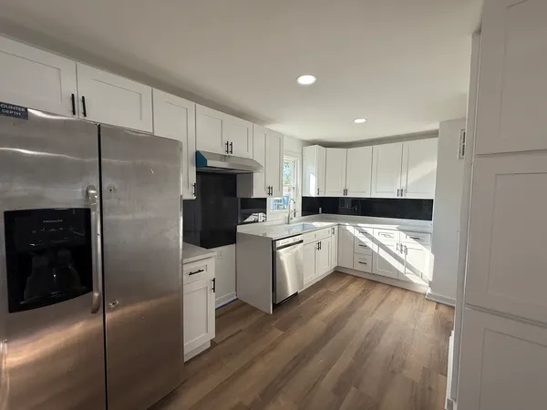 a large kitchen with cabinets wooden floor and stainless steel appliances