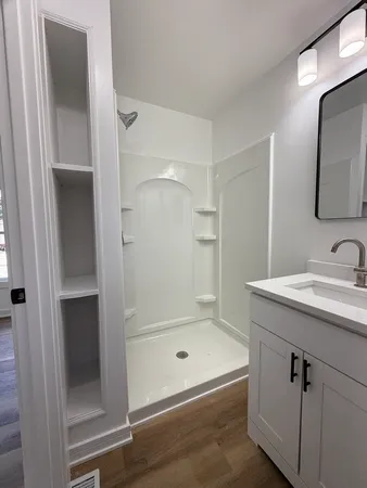 a bathroom with a shower a mirror and a sink