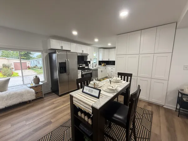 a kitchen with a refrigerator a stove a sink dishwasher with a dining table and chairs with wooden floor