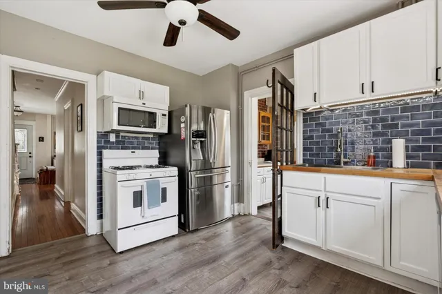 a kitchen with stainless steel appliances white cabinets and wooden floor