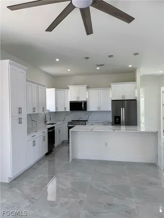 a view of an empty room with chandelier fan