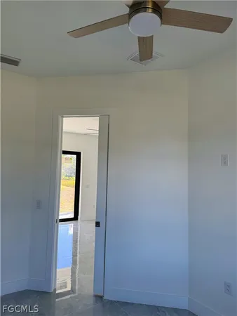 an empty room with a ceiling fan and window