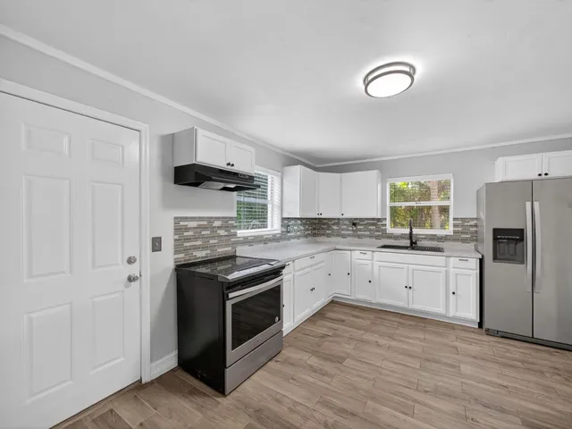 a kitchen with granite countertop white cabinets and stainless steel appliances