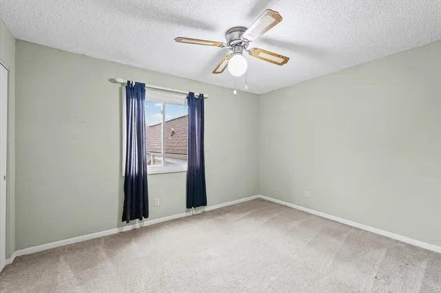 an empty room with a chandelier fan and windows