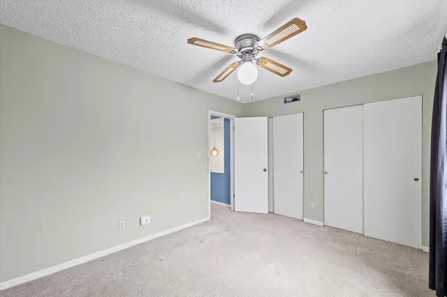 a view of an empty room with a chandelier fan
