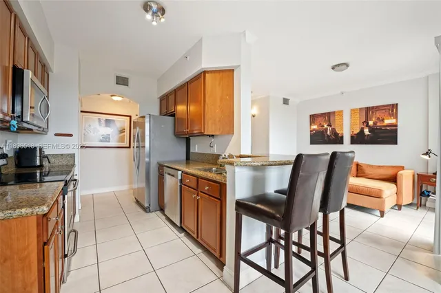 a kitchen with stainless steel appliances granite countertop a stove a sink a dining table and chairs