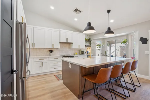 a open kitchen with stainless steel appliances granite countertop a sink a stove a refrigerator and island with wooden floor