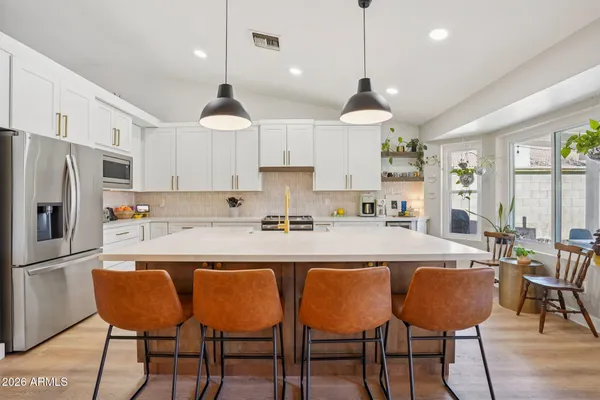 a kitchen with stainless steel appliances granite countertop a refrigerator a stove a sink dishwasher a dining table and chairs with wooden floor