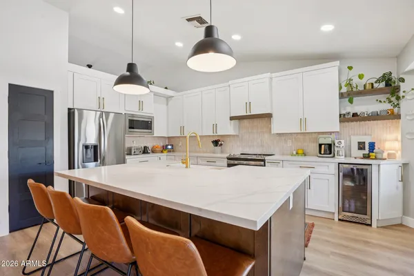 a kitchen with stainless steel appliances a stove a refrigerator a white table and chairs