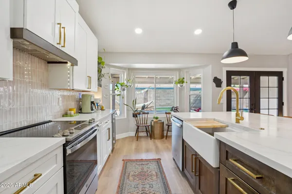 a kitchen with a stove a sink a kitchen island with windows and chairs