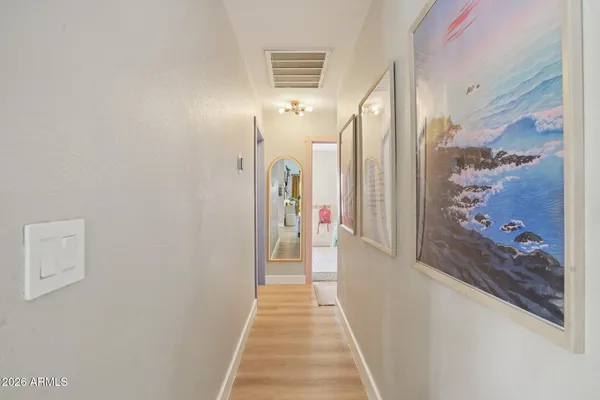 a view of a hallway with wooden floor and a bathroom