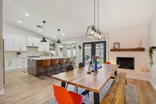 a living room with stainless steel appliances furniture a fireplace and a open kitchen view