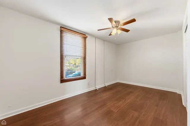 a view of an empty room with window and wooden floor