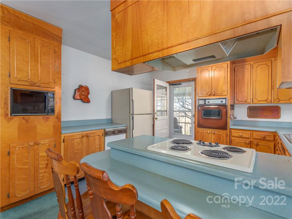 1179 Max Thompson Road Canton, NC 28716 - Photo 15 of 41 a kitchen with stainless steel appliances granite countertop a stove a refrigerator a dining table and chairs with wooden floor