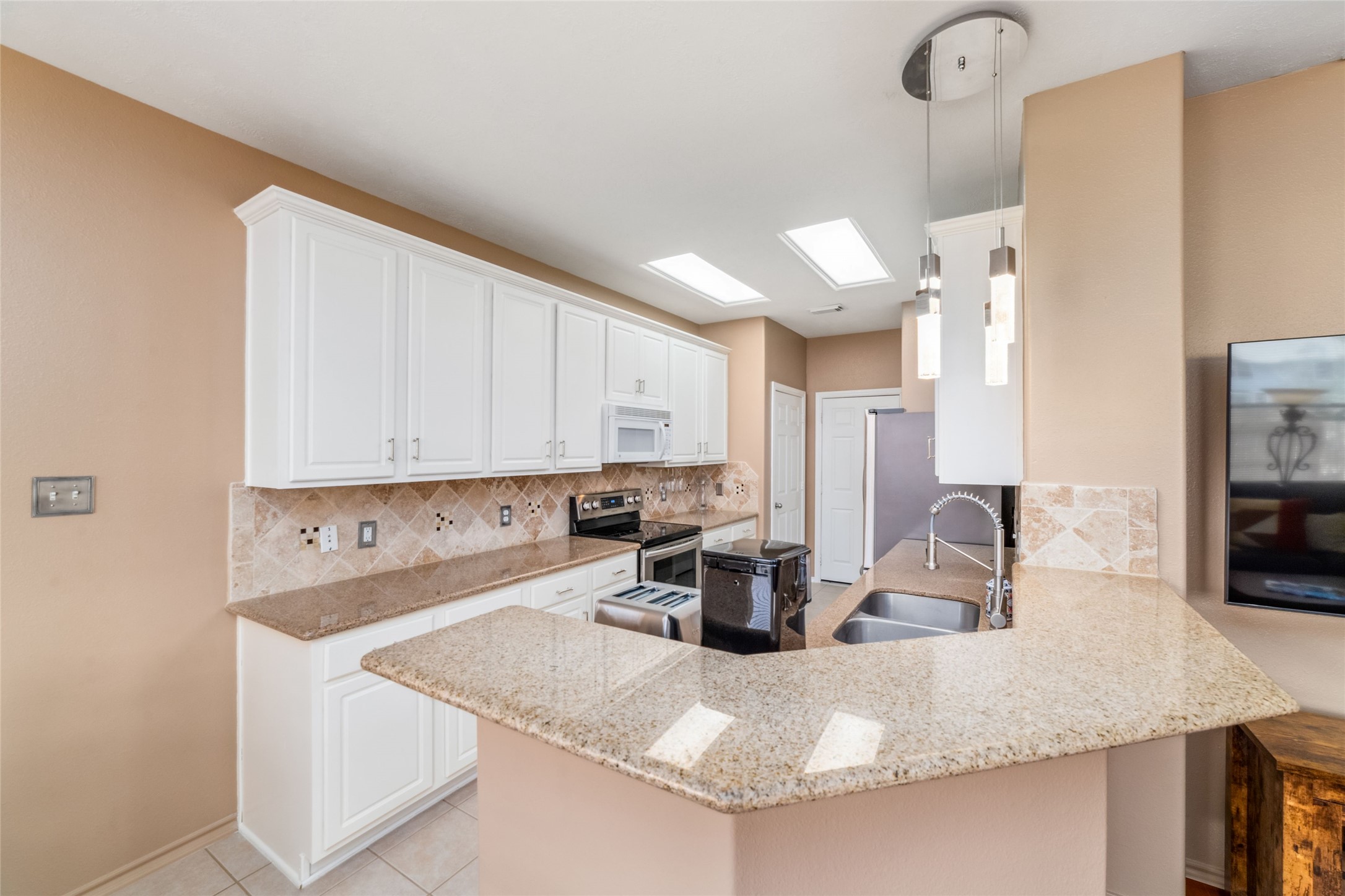 203 West Stedhill Loop Conroe, TX 77384 - Photo 9 of 45 a kitchen with kitchen island a sink a stove and a refrigerator with wooden floor