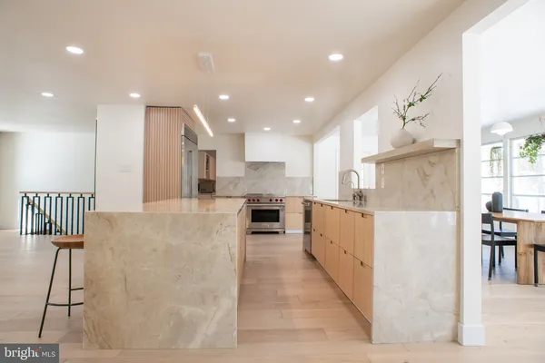 a large kitchen with stainless steel appliances kitchen island a large counter top a stove and a chandelier