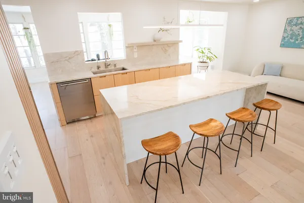 a kitchen with stainless steel appliances kitchen island a table chairs in it and wooden floor