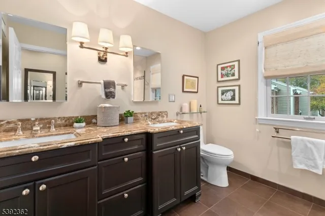 a bathroom with a toilet sink double vanity and mirror