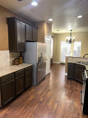 a kitchen with kitchen island granite countertop wooden floors stainless steel appliances and sink