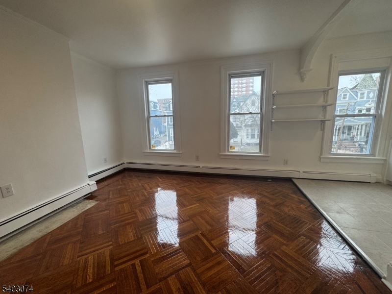 92 Cleveland Street Orange, NJ 07050 - Photo 11 of 16 an empty room with wooden floor and windows
