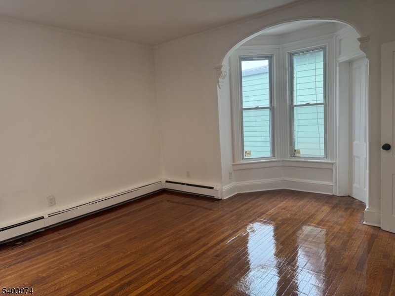 92 Cleveland Street Orange, NJ 07050 - Photo 13 of 16 a view of an empty room with wooden floor and a window