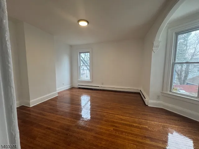 a view of empty room with window and wooden floor