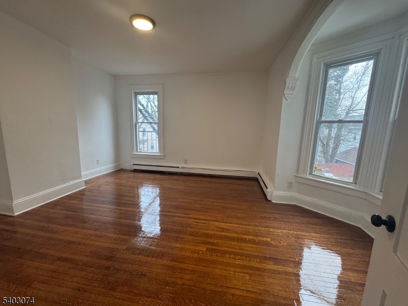 92 Cleveland Street Orange, NJ 07050 - Photo 15 of 16 a view of empty room with wooden floor and fan