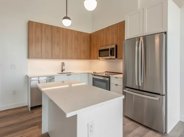 a kitchen with a sink a microwave a refrigerator and wooden floor