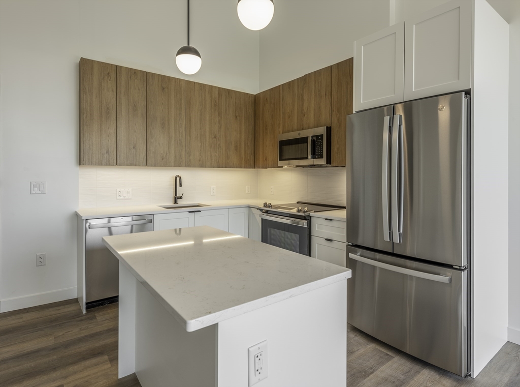 a kitchen with a sink a microwave a refrigerator and wooden floor
