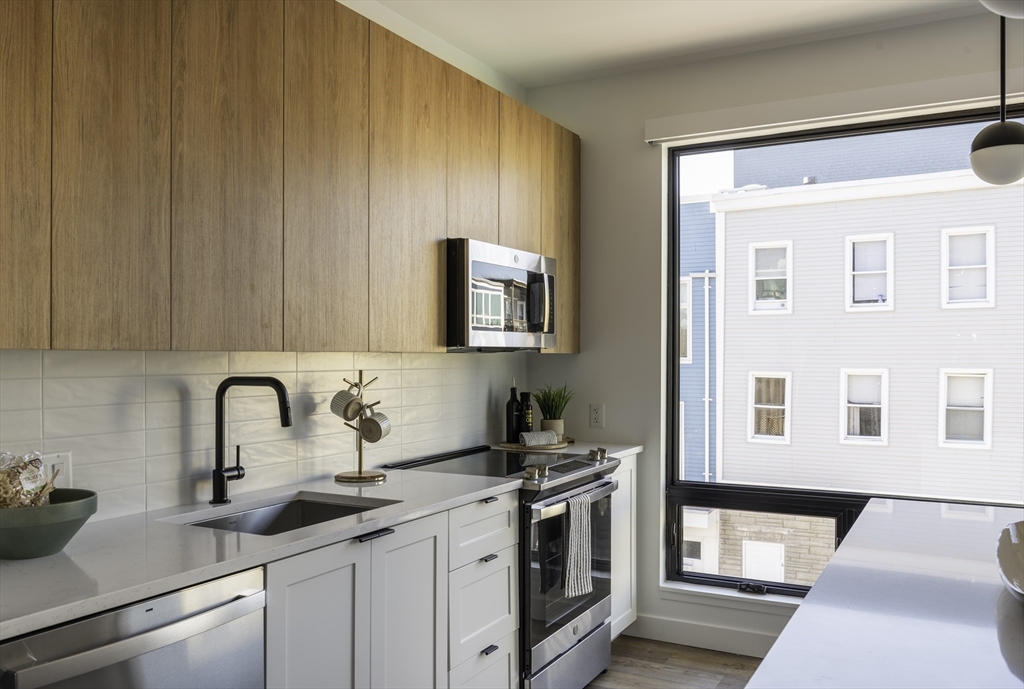 282 Bremen Street, Unit 237 Boston, MA 02128 - Photo 6 of 21 a kitchen with granite countertop a sink stainless steel appliances and cabinets